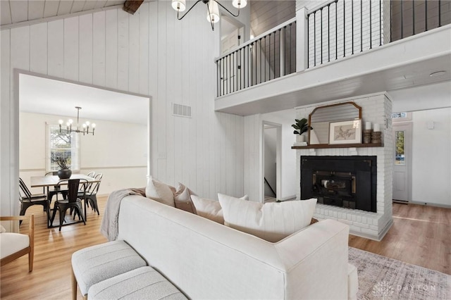 living room with wood-type flooring, high vaulted ceiling, wooden walls, and an inviting chandelier