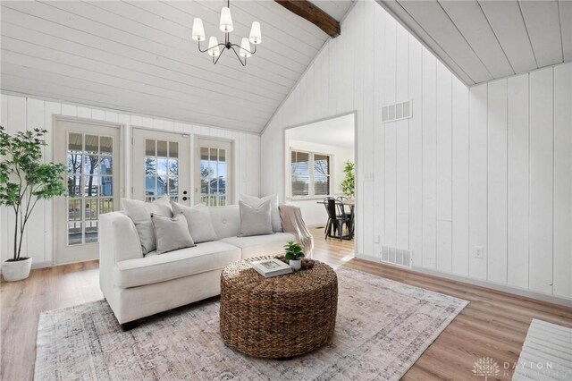 living room with high vaulted ceiling, beamed ceiling, light hardwood / wood-style flooring, an inviting chandelier, and french doors