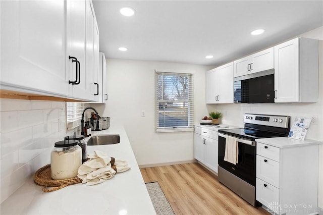 kitchen featuring white cabinetry, sink, decorative backsplash, and stainless steel electric range oven