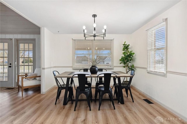 dining space with an inviting chandelier, french doors, and light wood-type flooring