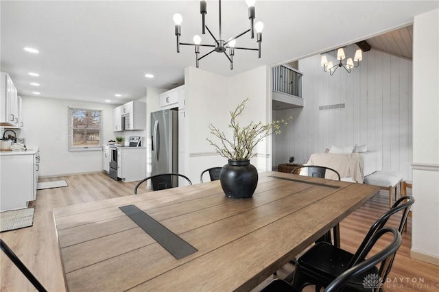 dining space featuring a chandelier, sink, and light hardwood / wood-style flooring