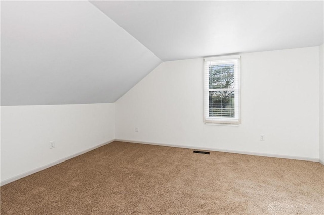 bonus room with vaulted ceiling and carpet flooring