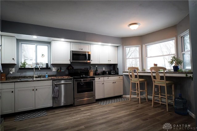 kitchen with stainless steel appliances, dark hardwood / wood-style flooring, sink, and white cabinets