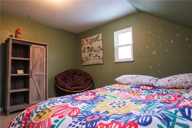 carpeted bedroom featuring a barn door and vaulted ceiling