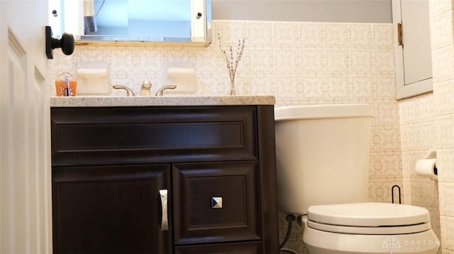 bathroom featuring vanity, tile walls, and toilet