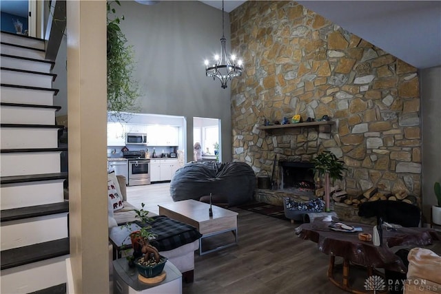 living room with a high ceiling, wood-type flooring, a fireplace, and an inviting chandelier