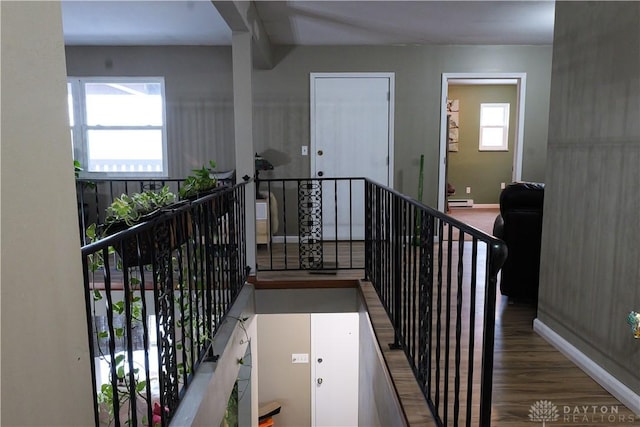 stairs featuring wood-type flooring and a baseboard heating unit