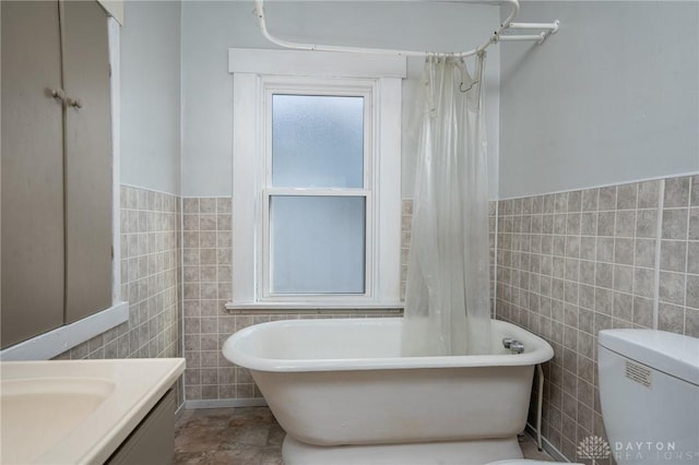 bathroom with vanity, toilet, and tile walls