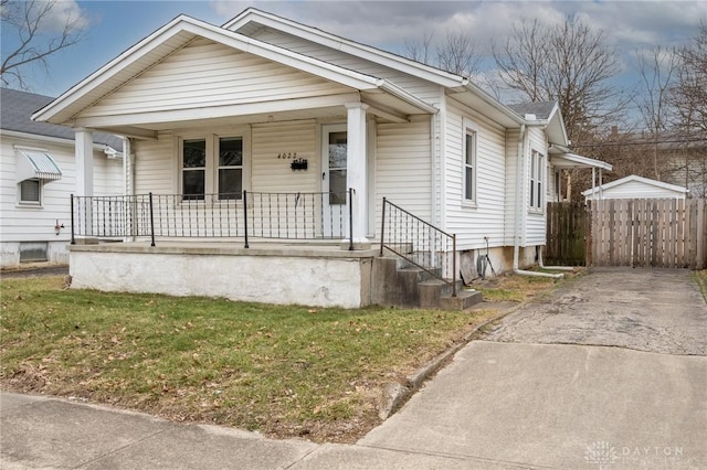 bungalow featuring covered porch, a front lawn, and fence