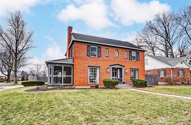 colonial inspired home featuring a sunroom and a front lawn