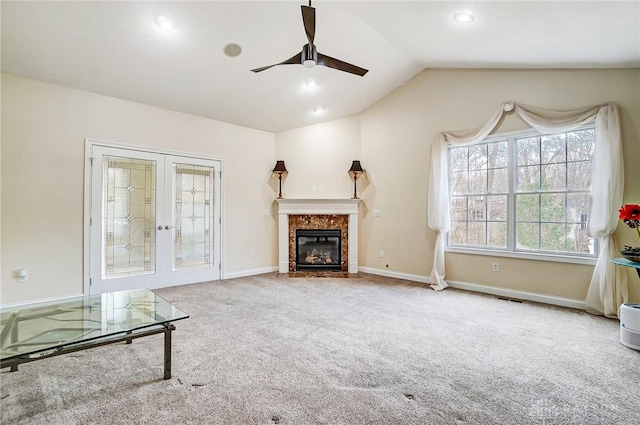 unfurnished living room featuring lofted ceiling, a premium fireplace, ceiling fan, carpet flooring, and french doors