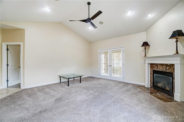 unfurnished living room with french doors, a high end fireplace, vaulted ceiling, ceiling fan, and carpet flooring