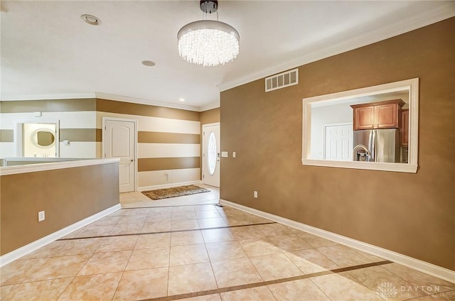 tiled foyer entrance with crown molding and an inviting chandelier