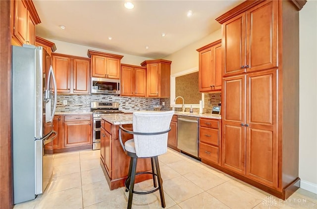 kitchen with a kitchen island, a breakfast bar, backsplash, light tile patterned floors, and stainless steel appliances