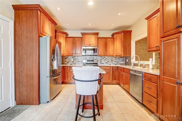 kitchen with a kitchen breakfast bar, sink, stainless steel appliances, and light tile patterned floors