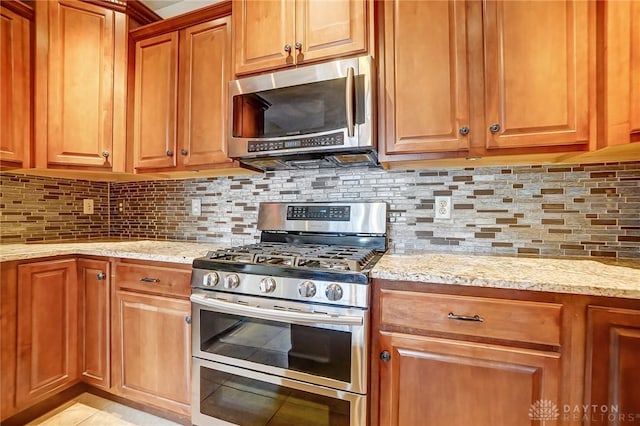 kitchen featuring backsplash, stainless steel appliances, and light stone counters