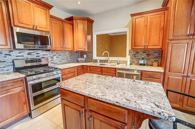 kitchen featuring appliances with stainless steel finishes, sink, decorative backsplash, light tile patterned floors, and light stone counters