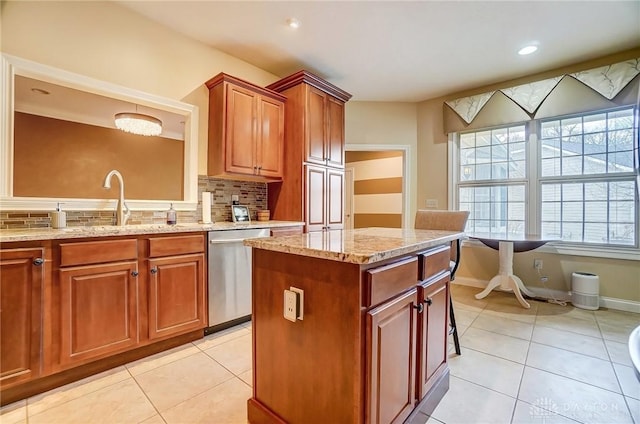 kitchen with light tile patterned floors, a kitchen island, light stone counters, and dishwasher