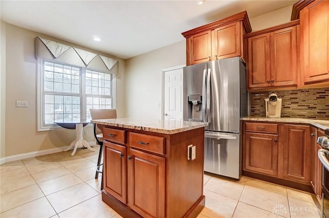 kitchen featuring stainless steel refrigerator with ice dispenser, light tile patterned flooring, light stone counters, and decorative backsplash