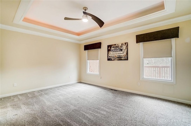 carpeted spare room featuring a tray ceiling, ornamental molding, and ceiling fan