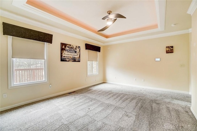 carpeted spare room featuring a tray ceiling, crown molding, and ceiling fan