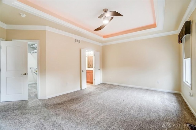 carpeted empty room with a raised ceiling, ceiling fan, and crown molding