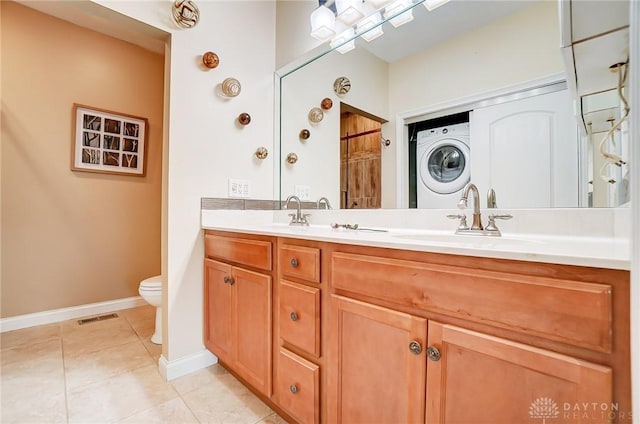 bathroom with stacked washer / drying machine, toilet, tile patterned flooring, and vanity