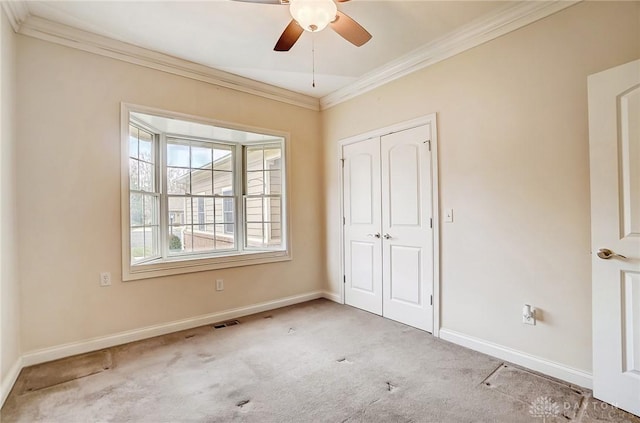 unfurnished bedroom featuring ceiling fan, a closet, crown molding, and light colored carpet