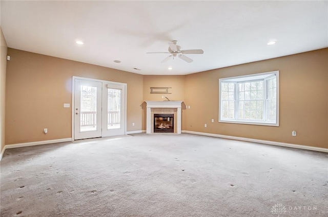 unfurnished living room with ceiling fan, light colored carpet, and a fireplace