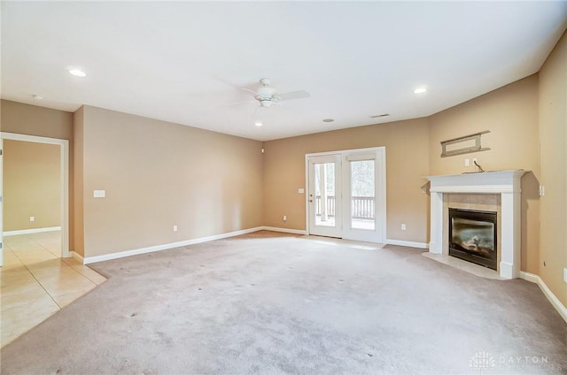 unfurnished living room featuring ceiling fan, a tiled fireplace, and light carpet