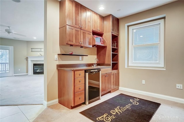 kitchen featuring light carpet, sink, dishwashing machine, and ceiling fan