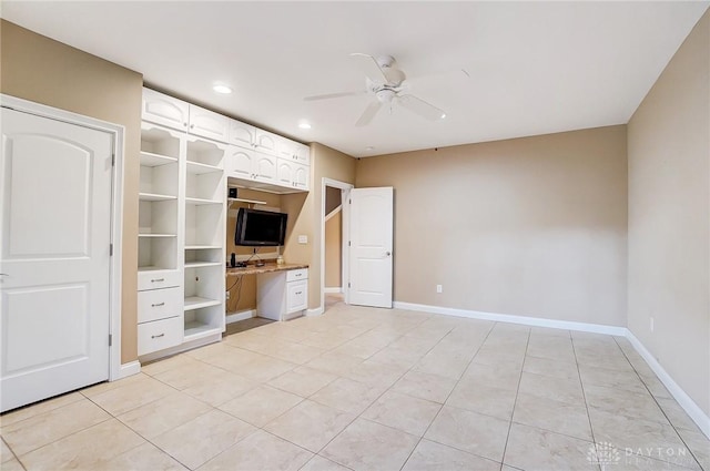 unfurnished bedroom with built in desk, ceiling fan, and light tile patterned flooring