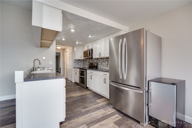 kitchen featuring sink, white cabinets, hardwood / wood-style flooring, stainless steel appliances, and backsplash