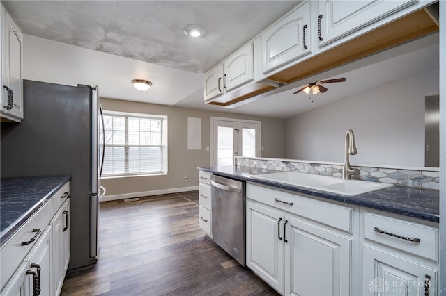 kitchen with sink, appliances with stainless steel finishes, dark hardwood / wood-style flooring, white cabinets, and backsplash