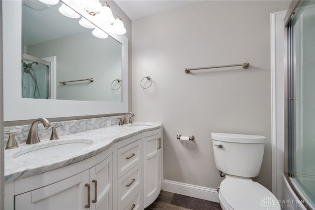 full bathroom featuring vanity, hardwood / wood-style floors, shower / bath combination with glass door, and toilet