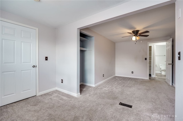 unfurnished bedroom featuring light colored carpet, ensuite bathroom, and a closet