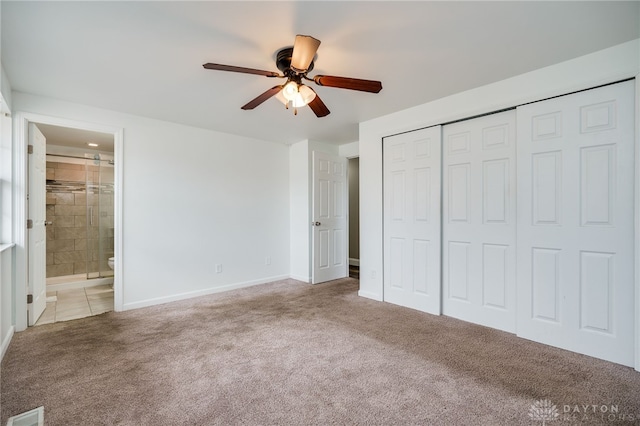 unfurnished bedroom featuring ensuite bathroom, carpet, ceiling fan, and a closet