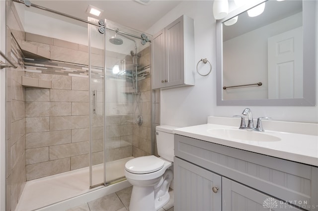 bathroom featuring a shower with door, vanity, tile patterned flooring, and toilet