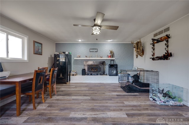 dining space with wood-type flooring, brick wall, and ceiling fan