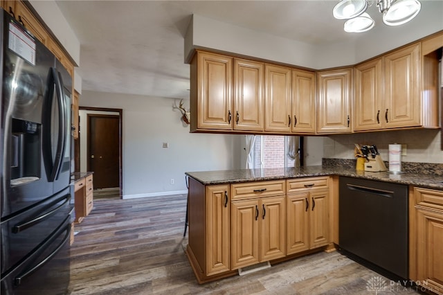 kitchen with refrigerator with ice dispenser, dark stone counters, kitchen peninsula, and dishwasher