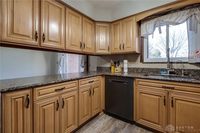 kitchen featuring dishwasher, sink, light hardwood / wood-style floors, and dark stone counters