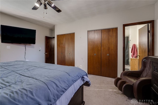 bedroom with two closets, light colored carpet, and ceiling fan