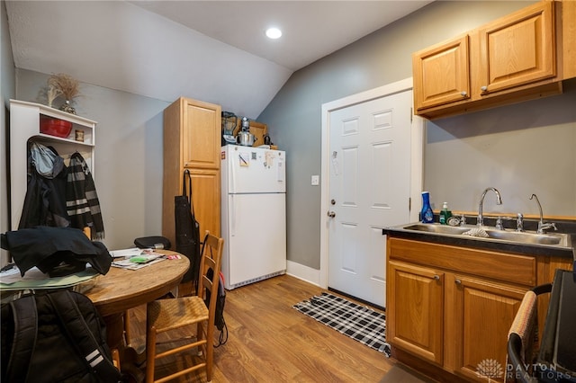 kitchen featuring sink, light hardwood / wood-style flooring, vaulted ceiling, and white fridge