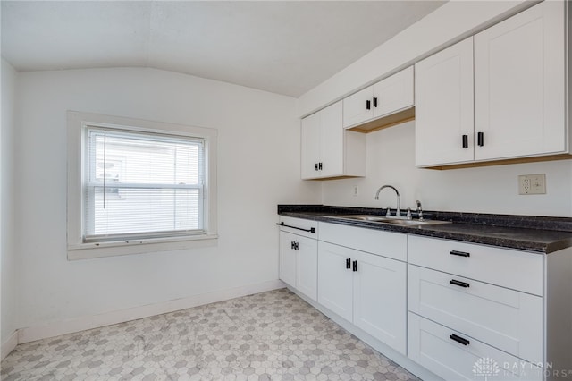 kitchen with lofted ceiling, sink, and white cabinets