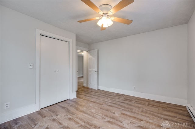 unfurnished bedroom with ceiling fan, a closet, baseboard heating, and light wood-type flooring