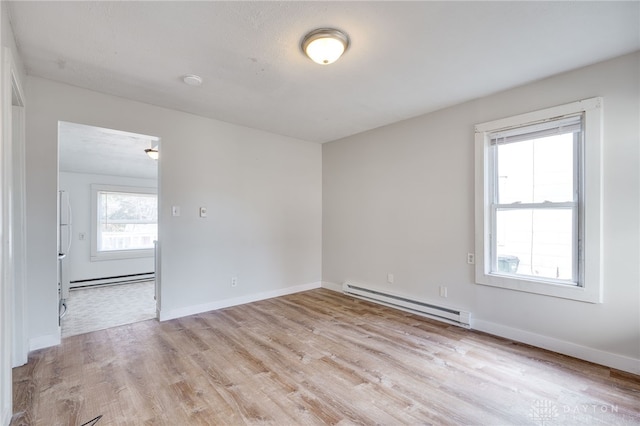 unfurnished room featuring a baseboard radiator and light hardwood / wood-style floors