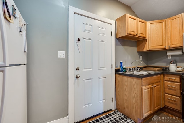 kitchen featuring white fridge, sink, and lofted ceiling