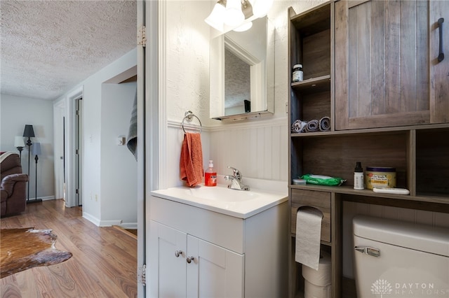 bathroom featuring vanity, wood-type flooring, a textured ceiling, and toilet