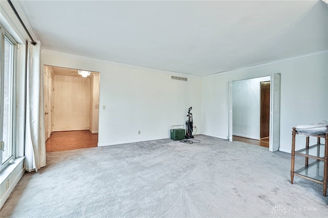 spare room with ornamental molding and light carpet