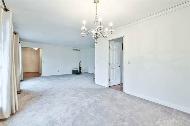 unfurnished room with an inviting chandelier, ornamental molding, and carpet